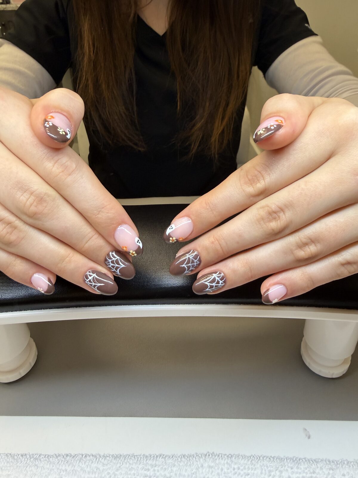 Halloween spiderweb nail art on mocha brown with pink French tips and tiny gold flowers