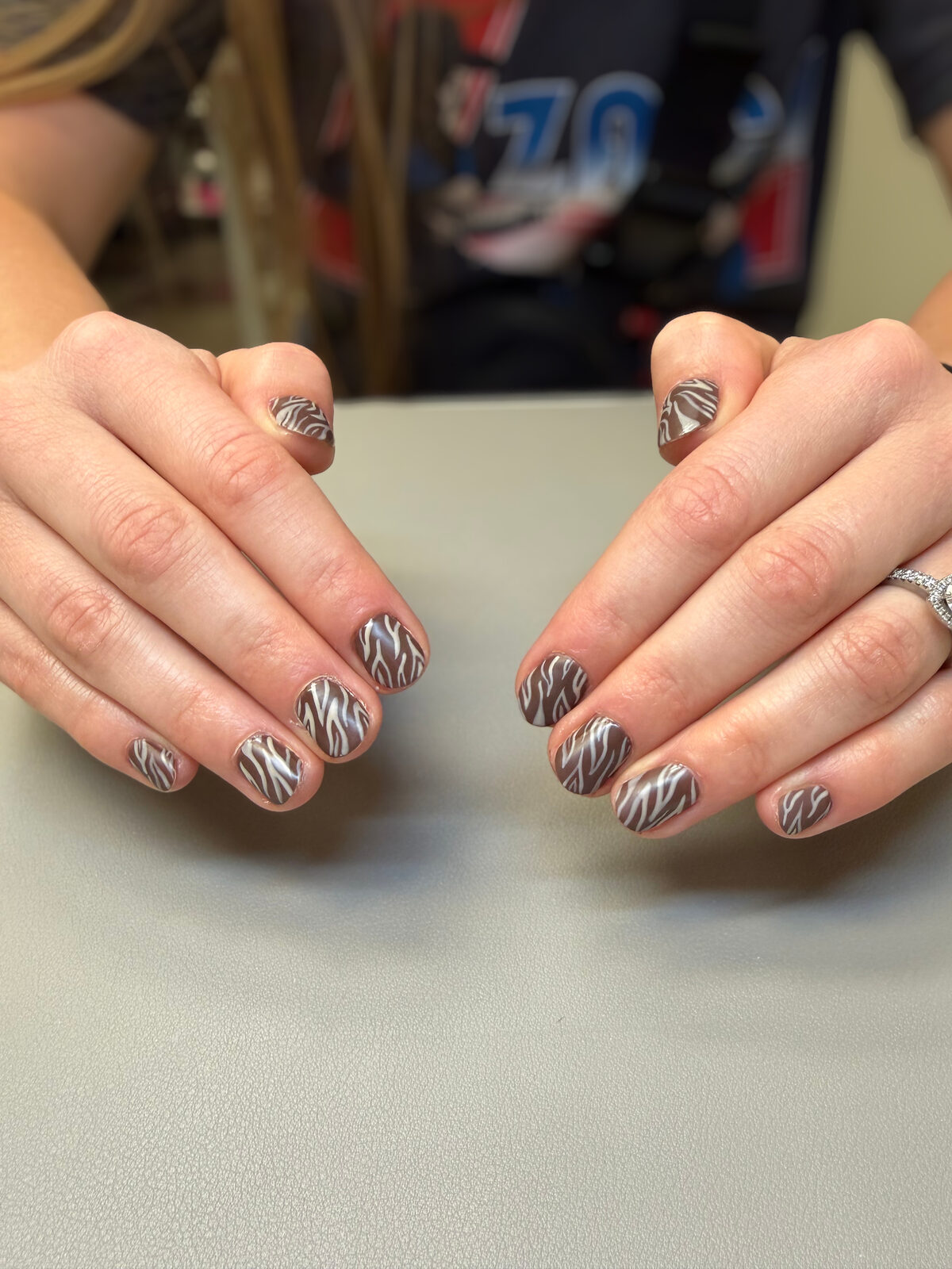 Brown and white zebra print nail art on short round nails